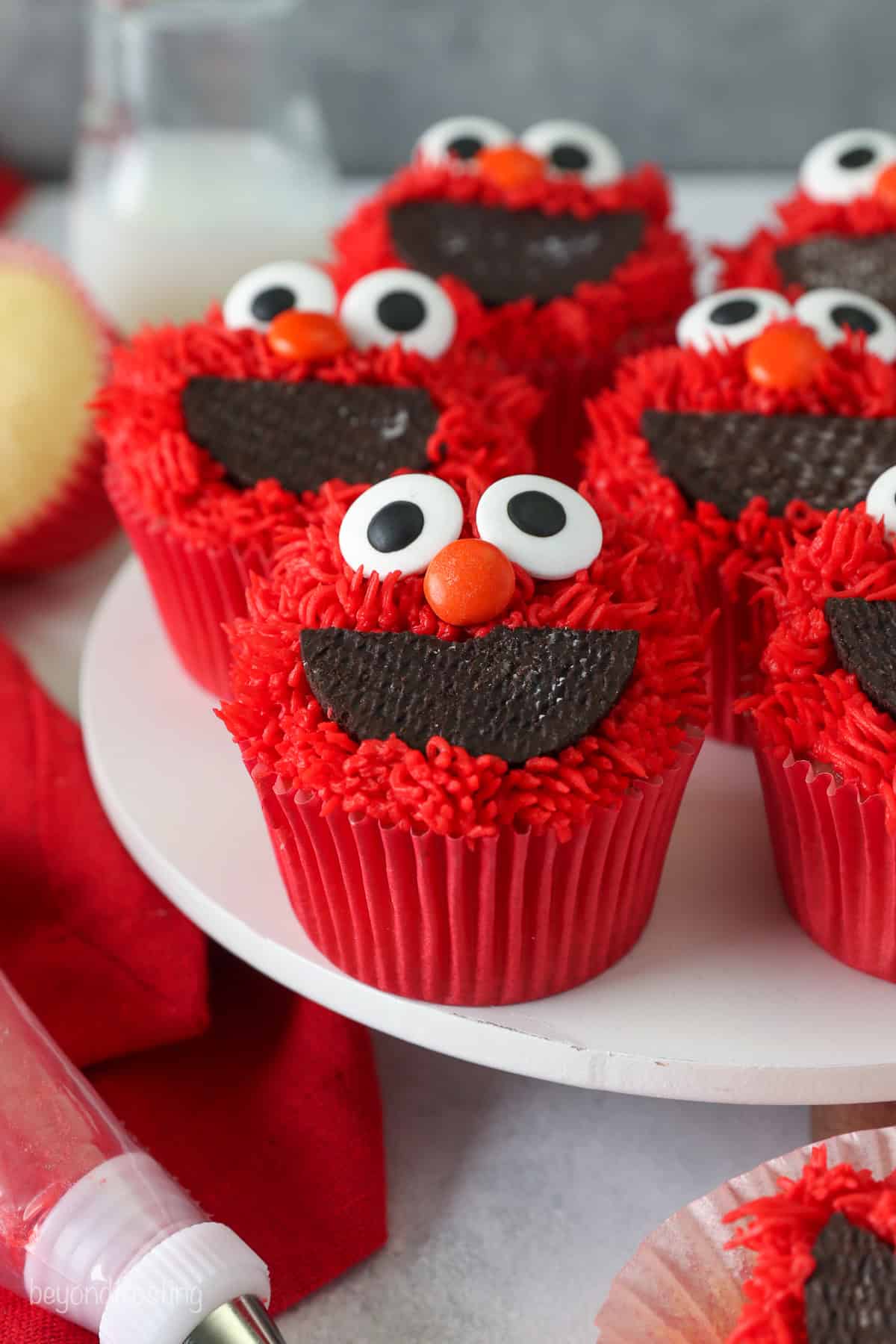 Decorated Elmo cupcakes on a white cake stand.