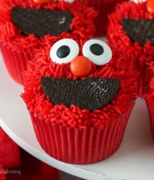 Close up of Elmo cupcakes on a white cake stand.