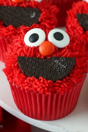 Close up of Elmo cupcakes on a white cake stand.