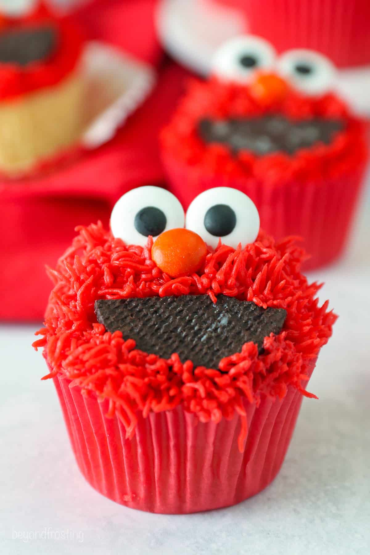 Close up of a finished Elmo cupcake on a white countertop.