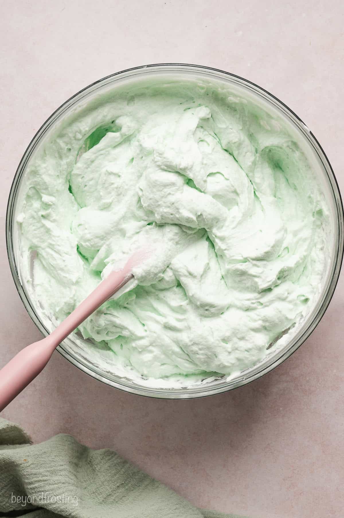 Whipped grasshopper pie filling in a bowl with a spatula.
