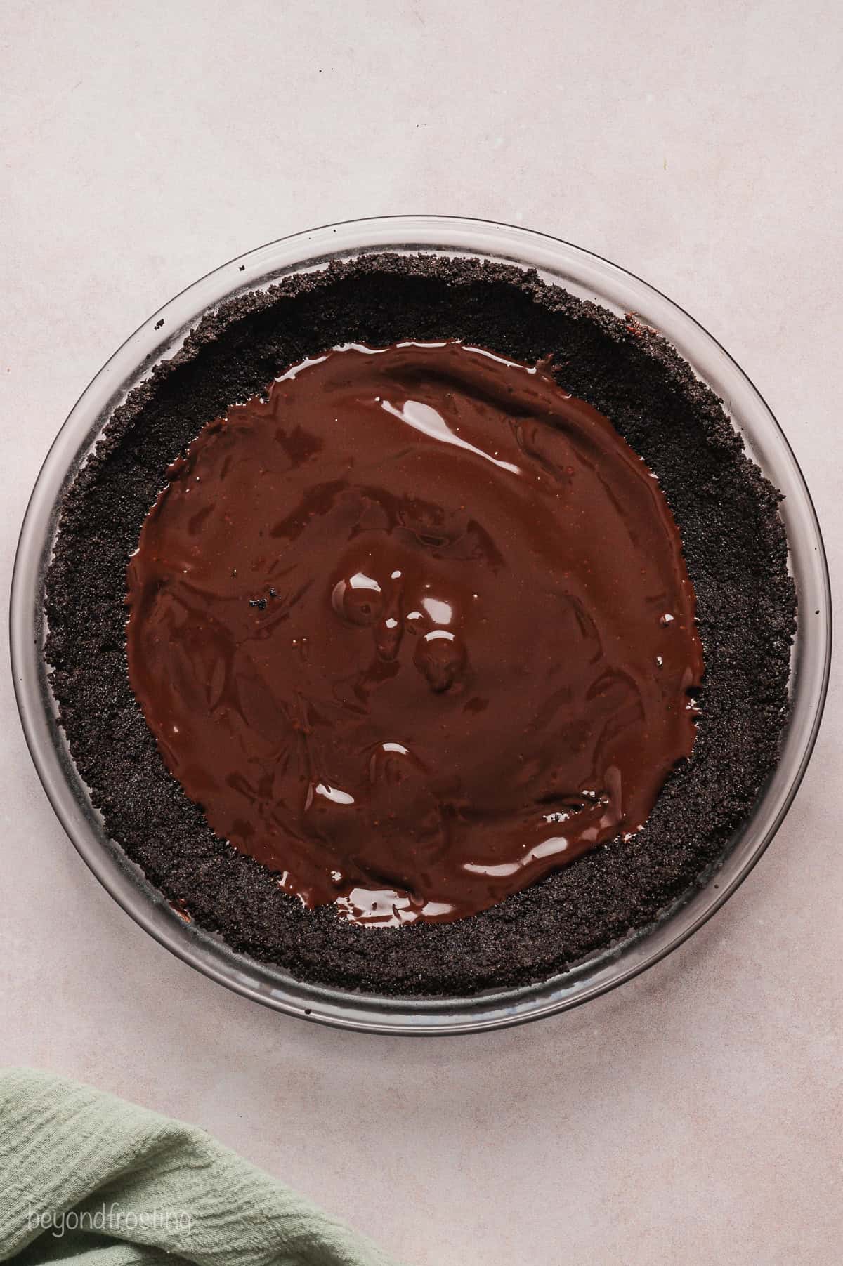 Chocolate ganache added to an Oreo crust inside a pie plate.