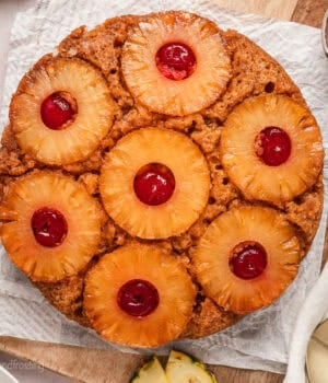 Overhead view of a pineapple upside down cake on a parchment-lined cutting board.