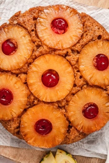 Overhead view of a pineapple upside down cake on a parchment-lined cutting board.