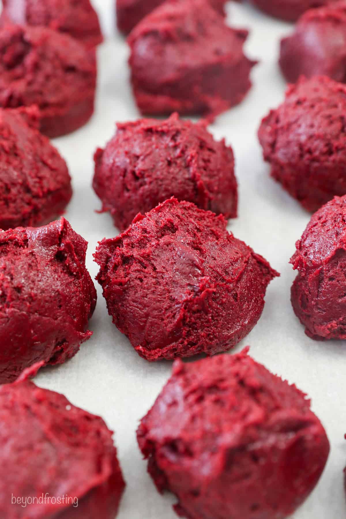 Scoops of red velvet cake mix cookie dough in rows.