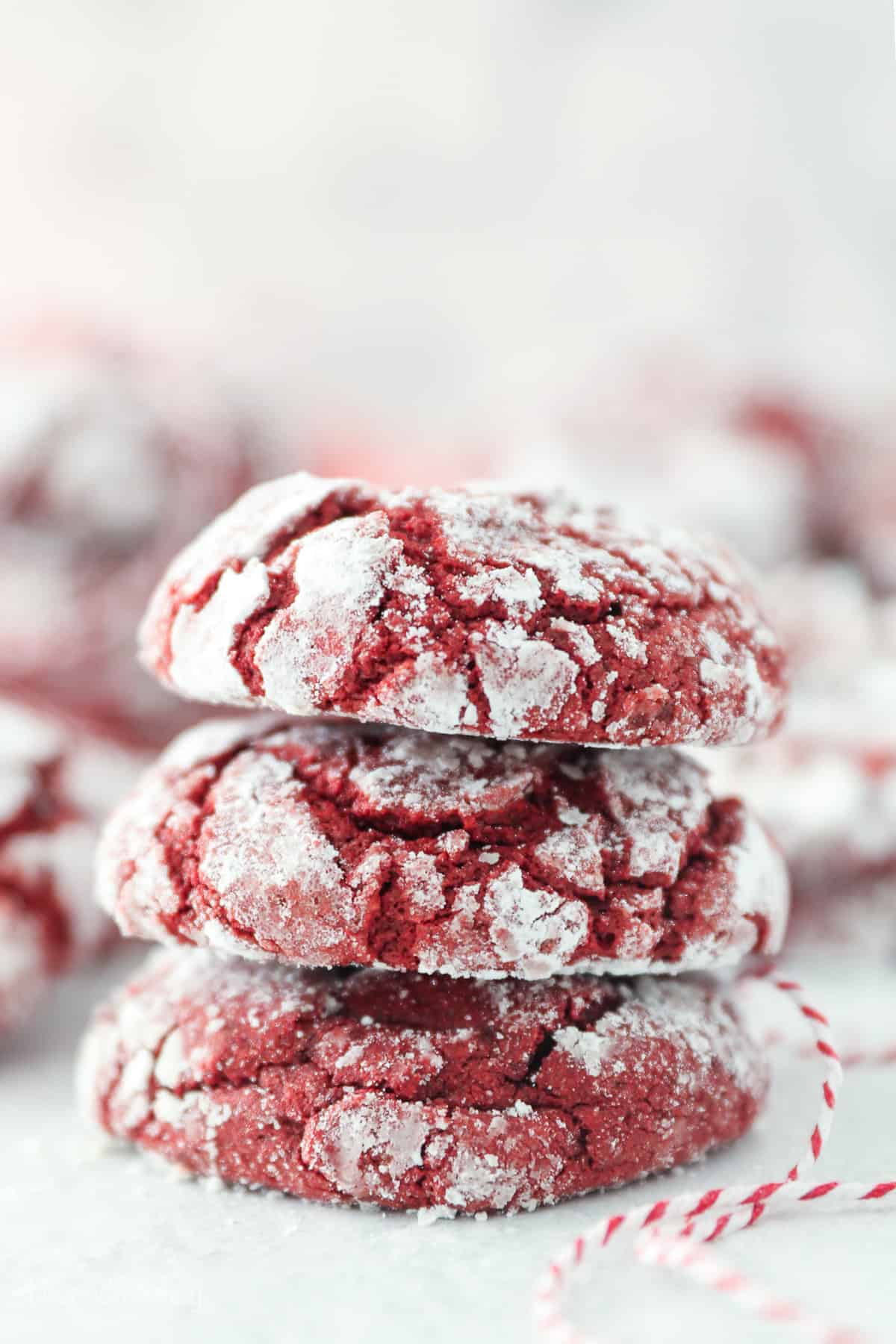 Side view of three red velvet cake mix cookies stacked on a countertop.