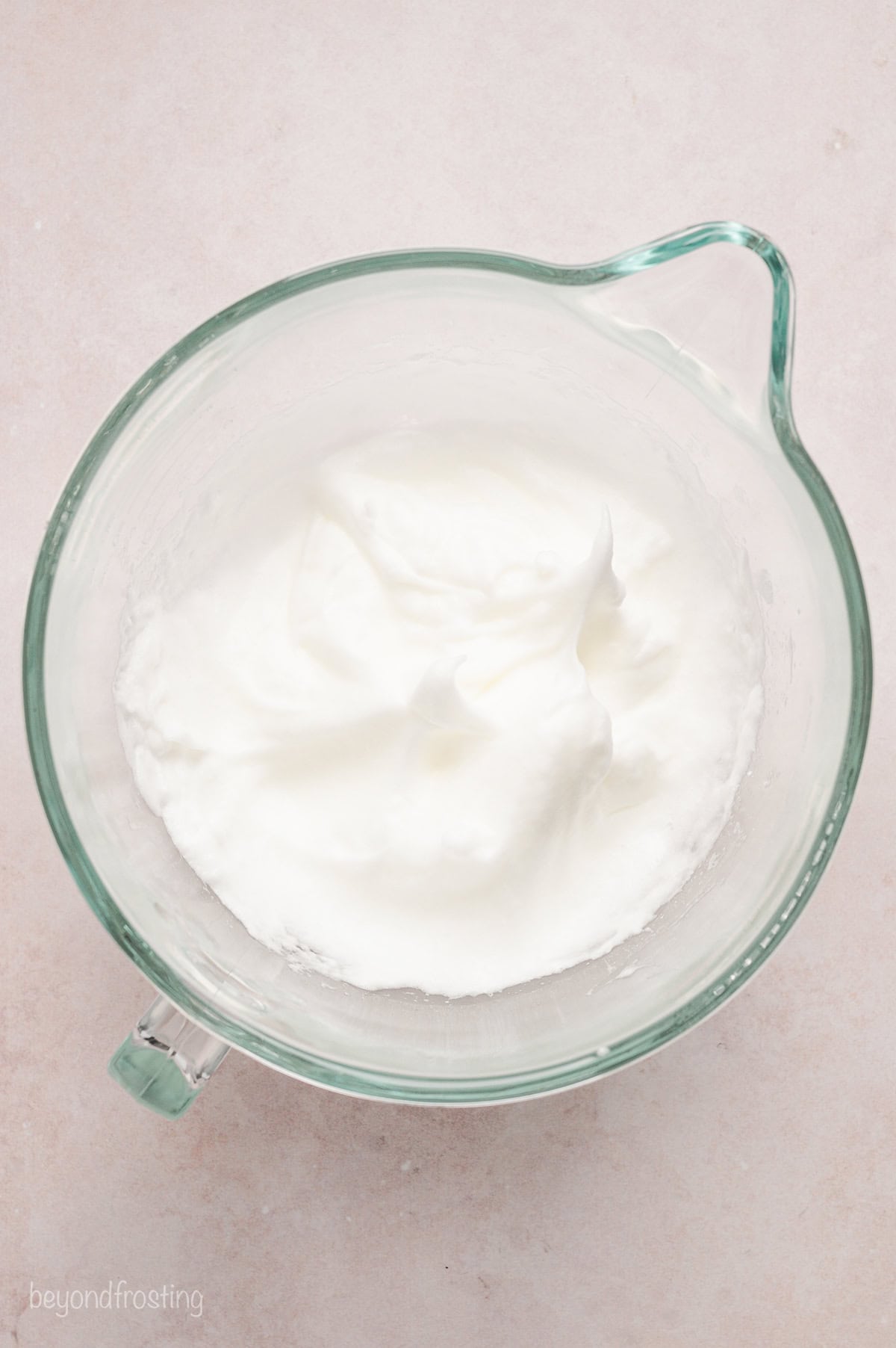 Whipped egg whites in a glass mixing bowl.