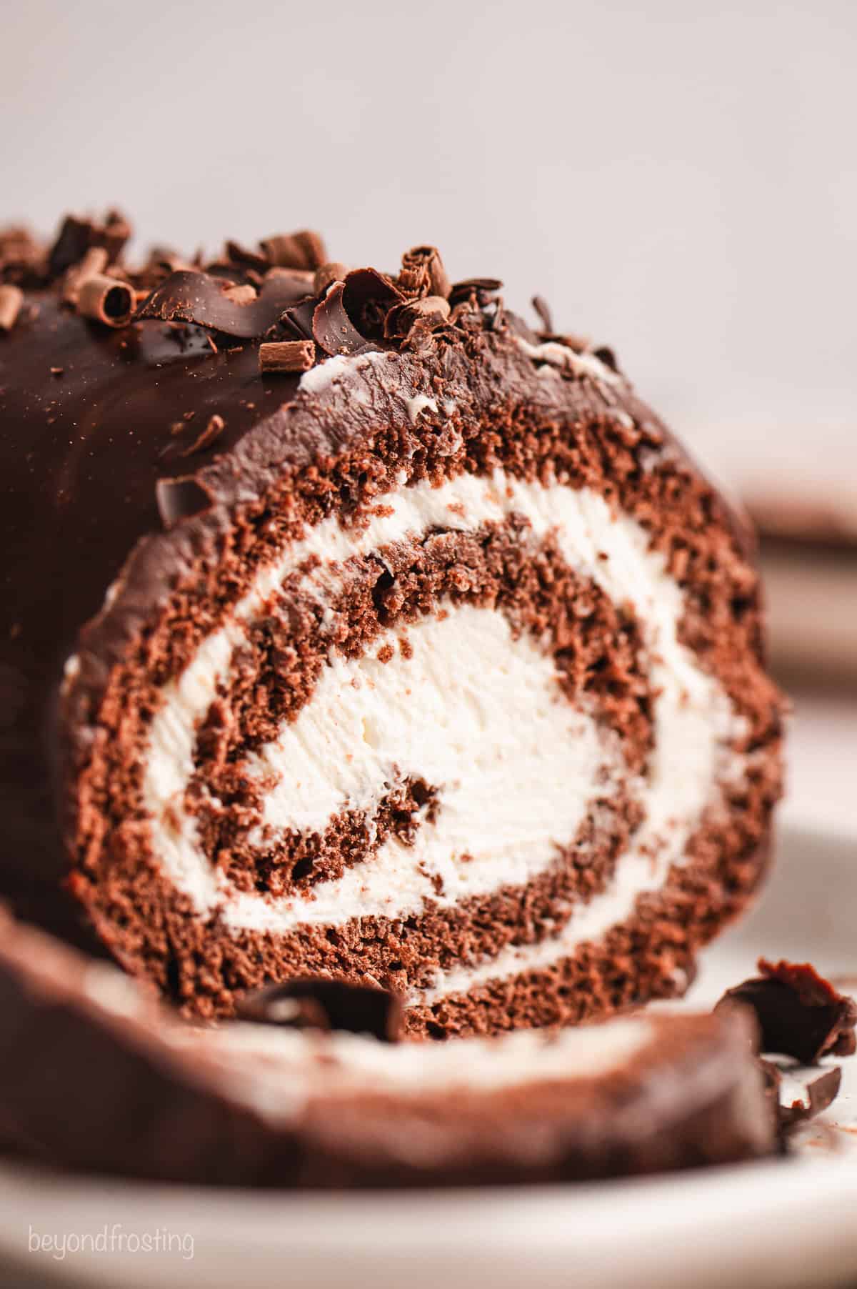 Close up of a chocolate cake roll topped with chocolate shavings.