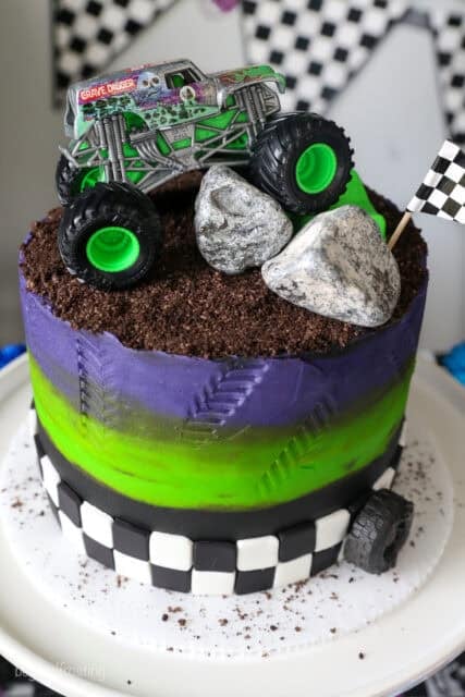 Close up of a Gravedigger monster truck cake on a white cake stand.
