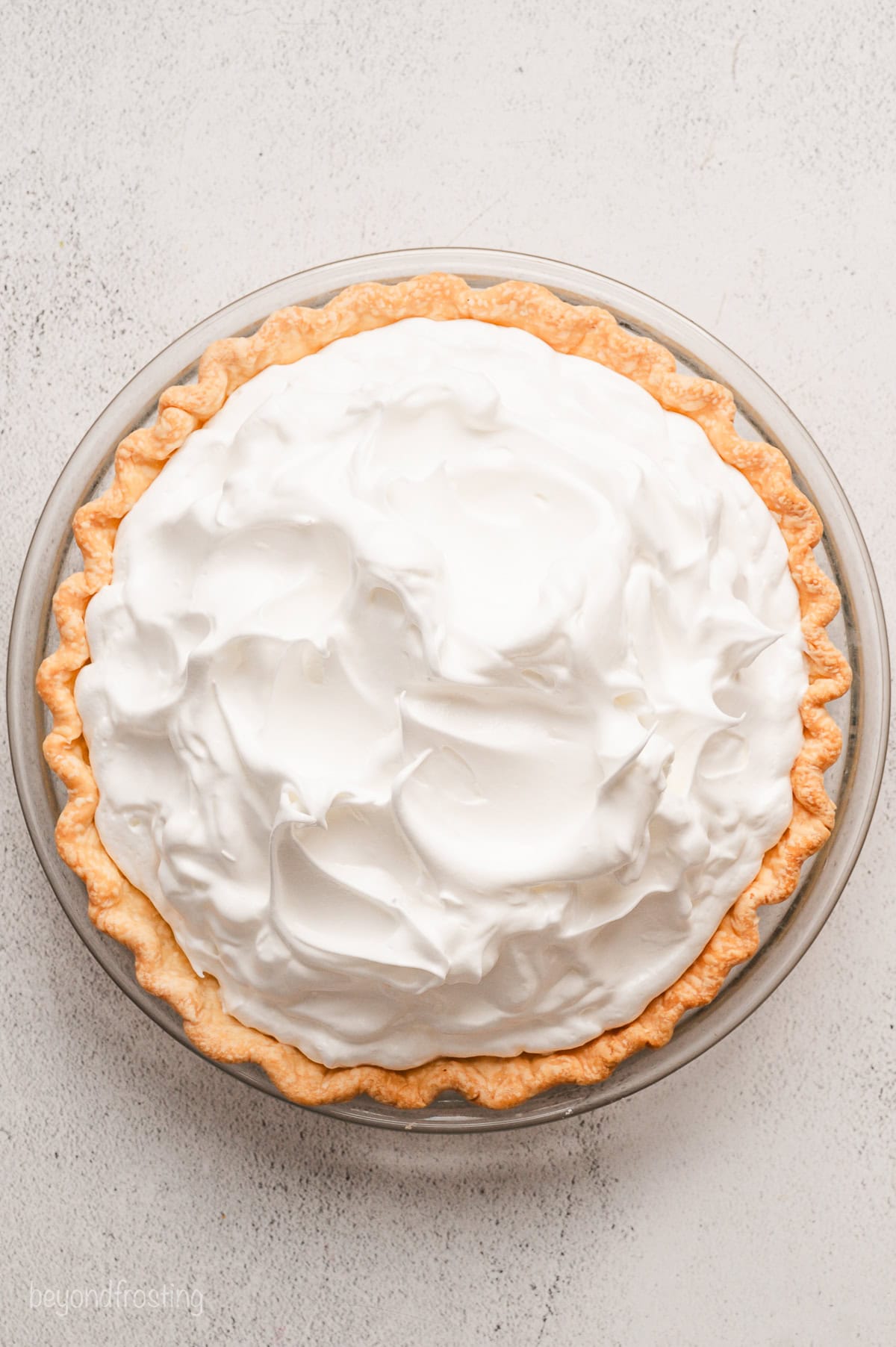 Overhead view of a lemon meringue pie topped with meringue in a pie plate.