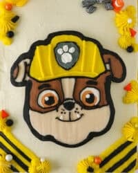 Overhead view of a Rubble Paw Patrol Cake with Rubble's detailed face in the center, decorated with a buttercream transfer.