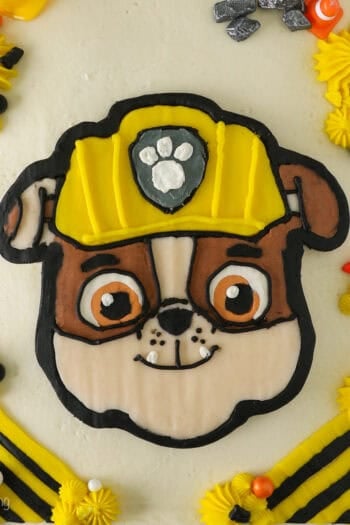 Overhead view of a Rubble Paw Patrol Cake with Rubble's detailed face in the center, decorated with a buttercream transfer.