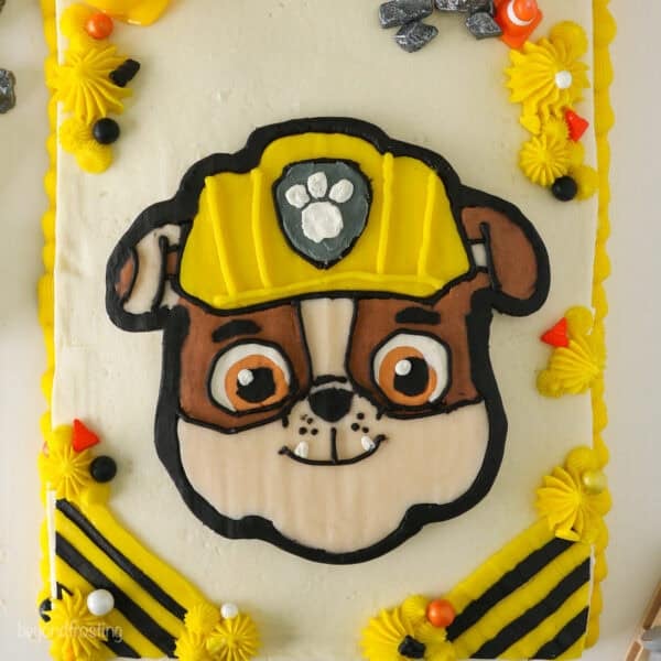 Overhead view of a Rubble Paw Patrol Cake with Rubble's detailed face in the center, decorated with a buttercream transfer.