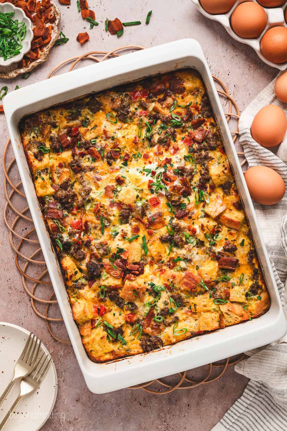 This easy make-ahead breakfast egg casserole is perfect for weekend brunch, filled with fresh eggs, sourdough, bacon, sausage, and cheese. Overhead view of a breakfast egg casserole in a baking dish.
