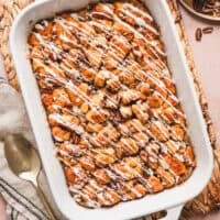 Overhead view of a cinnamon roll casserole drizzled with cream cheese icing in a baking dish.