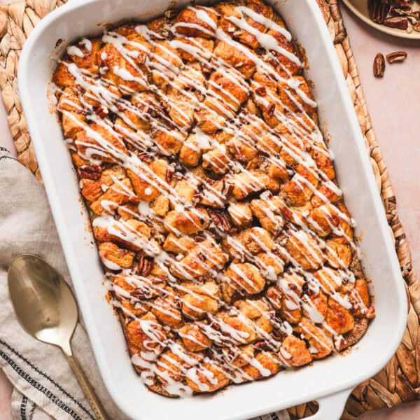 Overhead view of a cinnamon roll casserole drizzled with cream cheese icing in a baking dish.