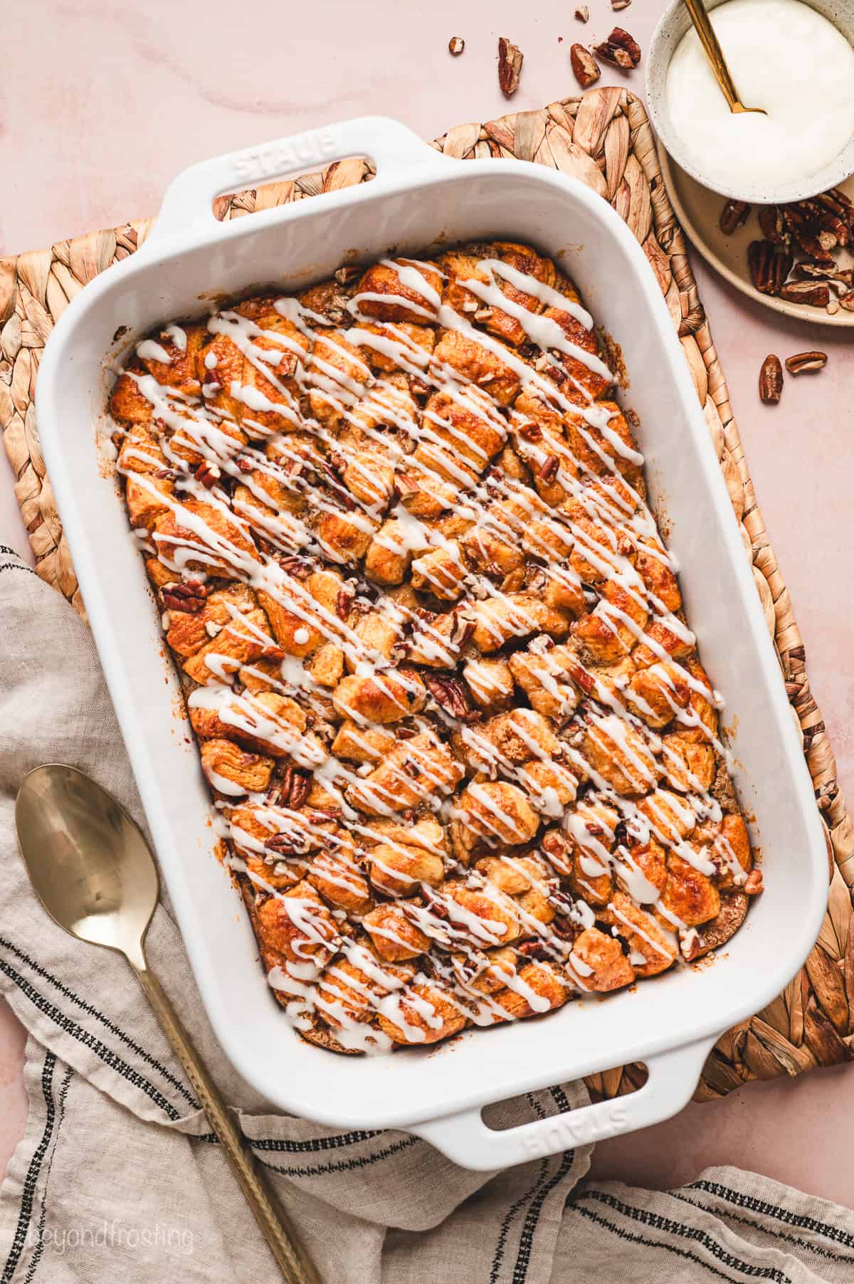 Make this cinnamon roll casserole with refrigerated cinnamon rolls and homemade cream cheese icing baked to ooey-gooey, golden perfection. Overhead view of a cinnamon roll casserole drizzled with cream cheese icing in a baking dish.