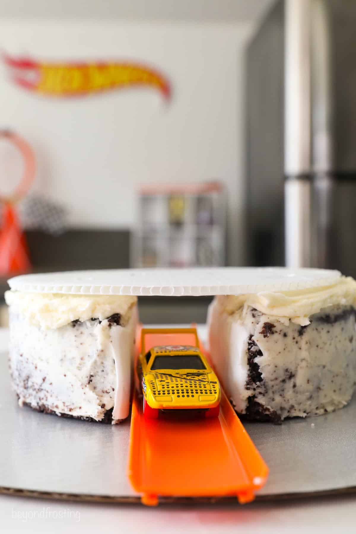 A toy car passing through a Hot Wheels track set through the bottom cake layer.