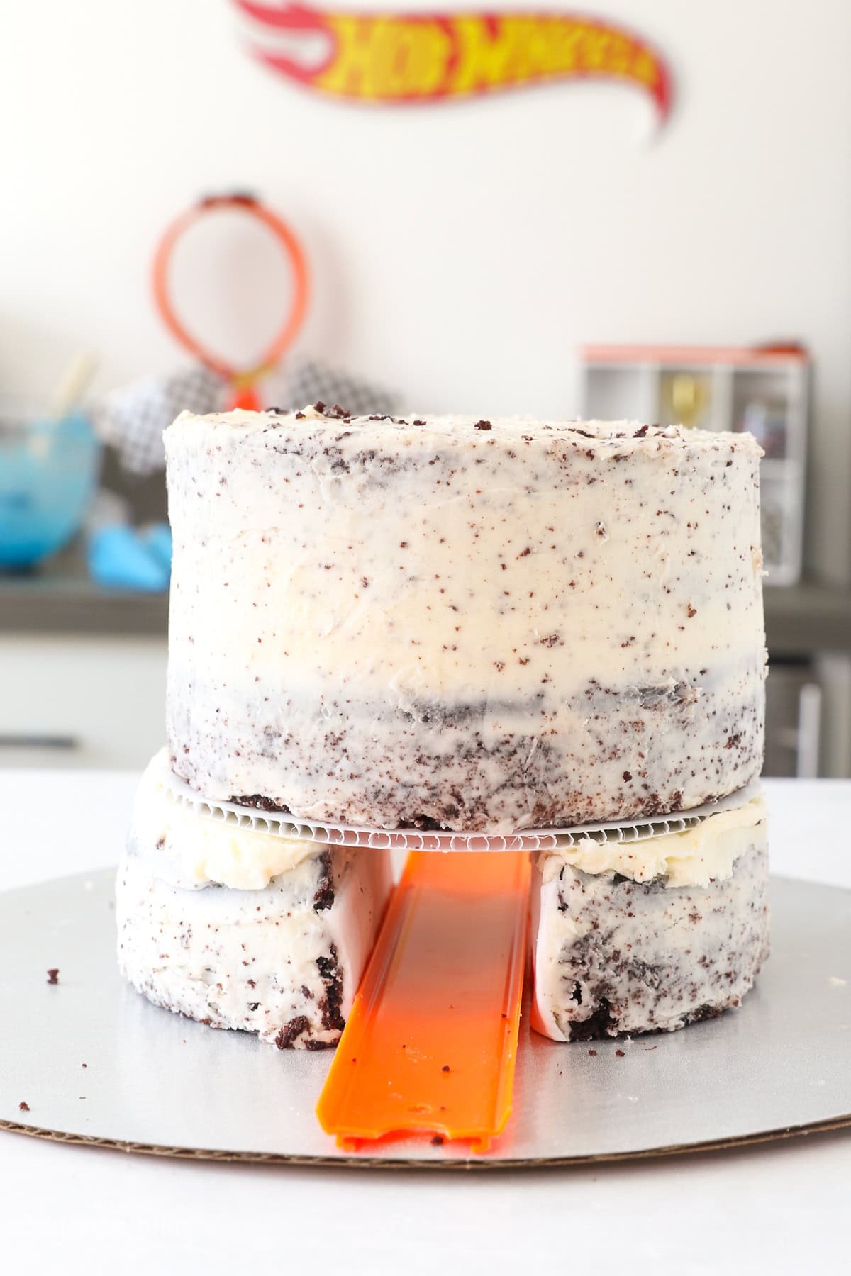 A layer cake frosted with a crumb coat, with a tunnel through the bottom of the cake.