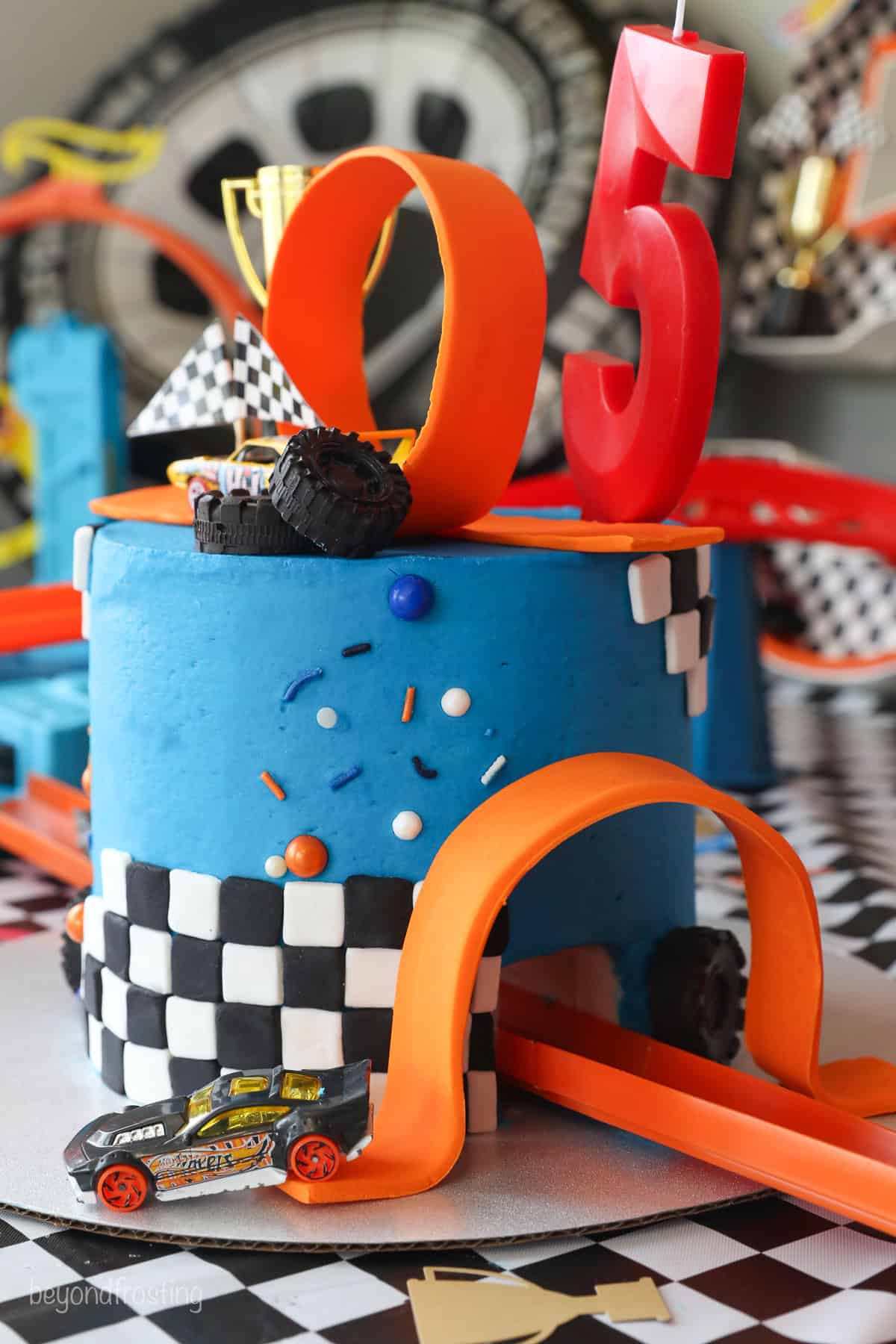 An angled view of a Hot Wheels cake showing a toy car coming through the tunnel that runs through the cake.