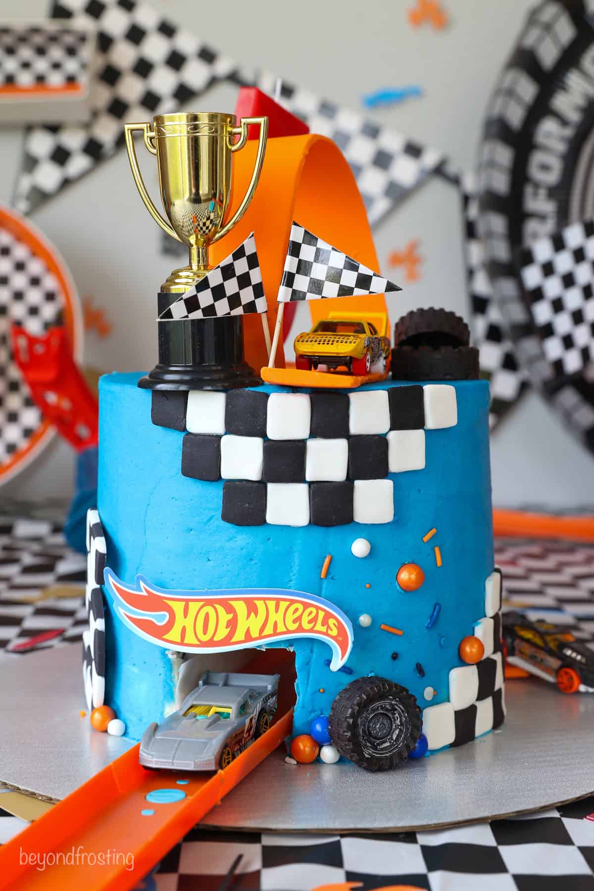 An angled view of a Hot Wheels cake showing a toy car coming through the tunnel that runs through the cake.