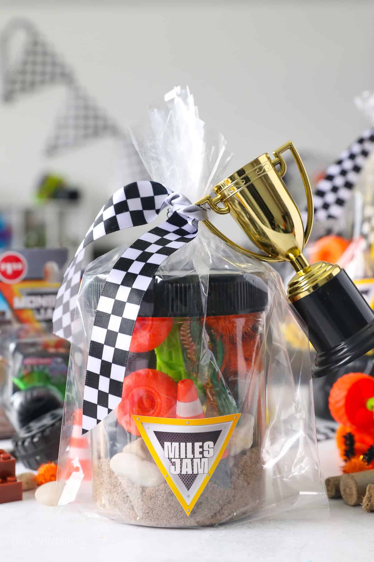A Monster Jam play dough kit wrapped inside cellophane tied with a checkered ribbon.