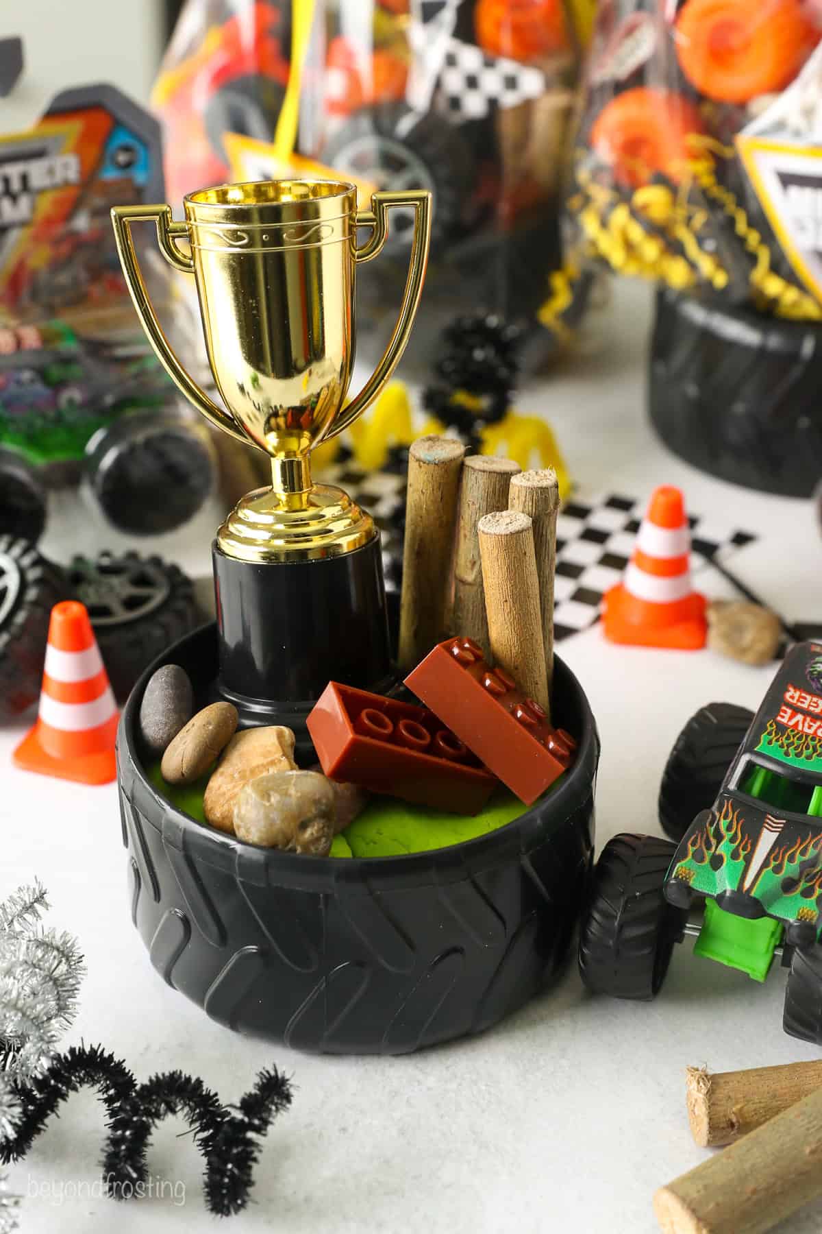 A tire bowl filled with Monster truck party favors, including mini logs, Legos, and a toy trophy.
