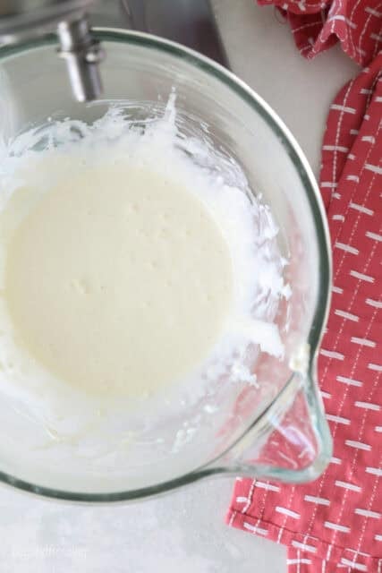 a close up of a stand mixer glass bowl with heavy cream