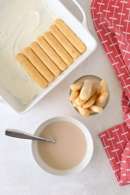 a bowl of milk, ladyfingers and a pan half filled with ladyfinger