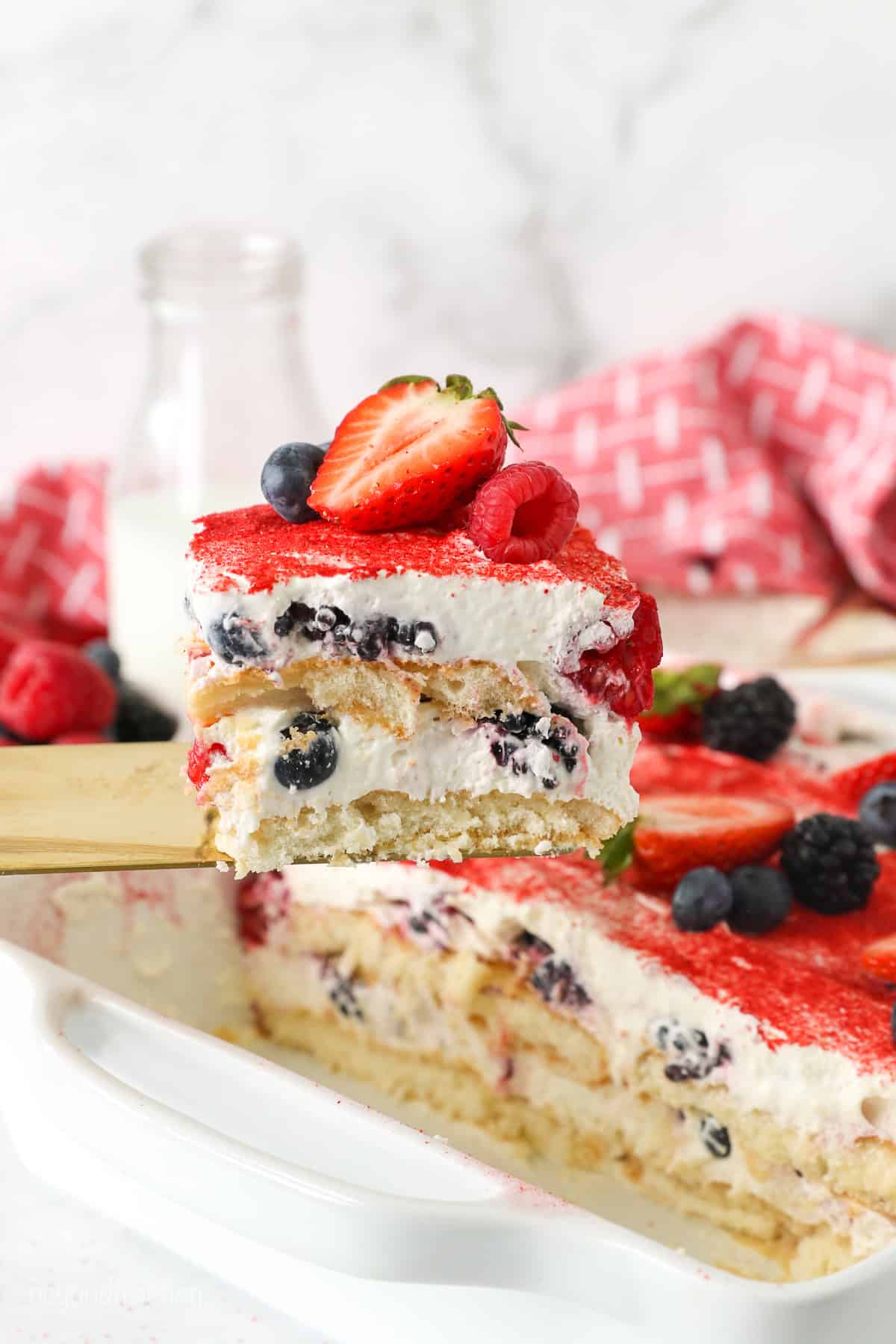A spatula holding a slice of layered berry Tiramisu