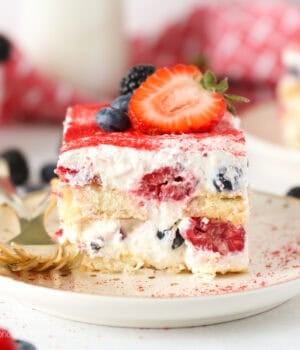 A close up of a slice of layered Berry Tiramisu with 2 forks on a. plate.