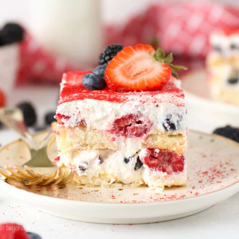 A close up of a slice of layered Berry Tiramisu with 2 forks on a. plate.