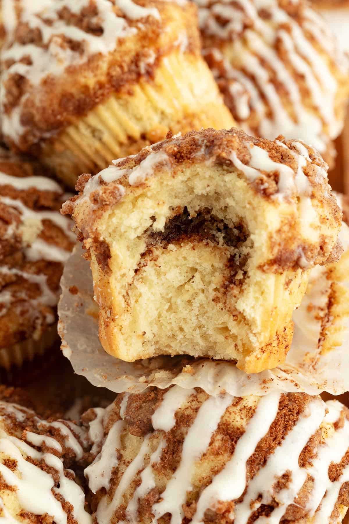 Close up of a coffee cake muffin with a bite missing, revealing the swirled cinnamon filling.