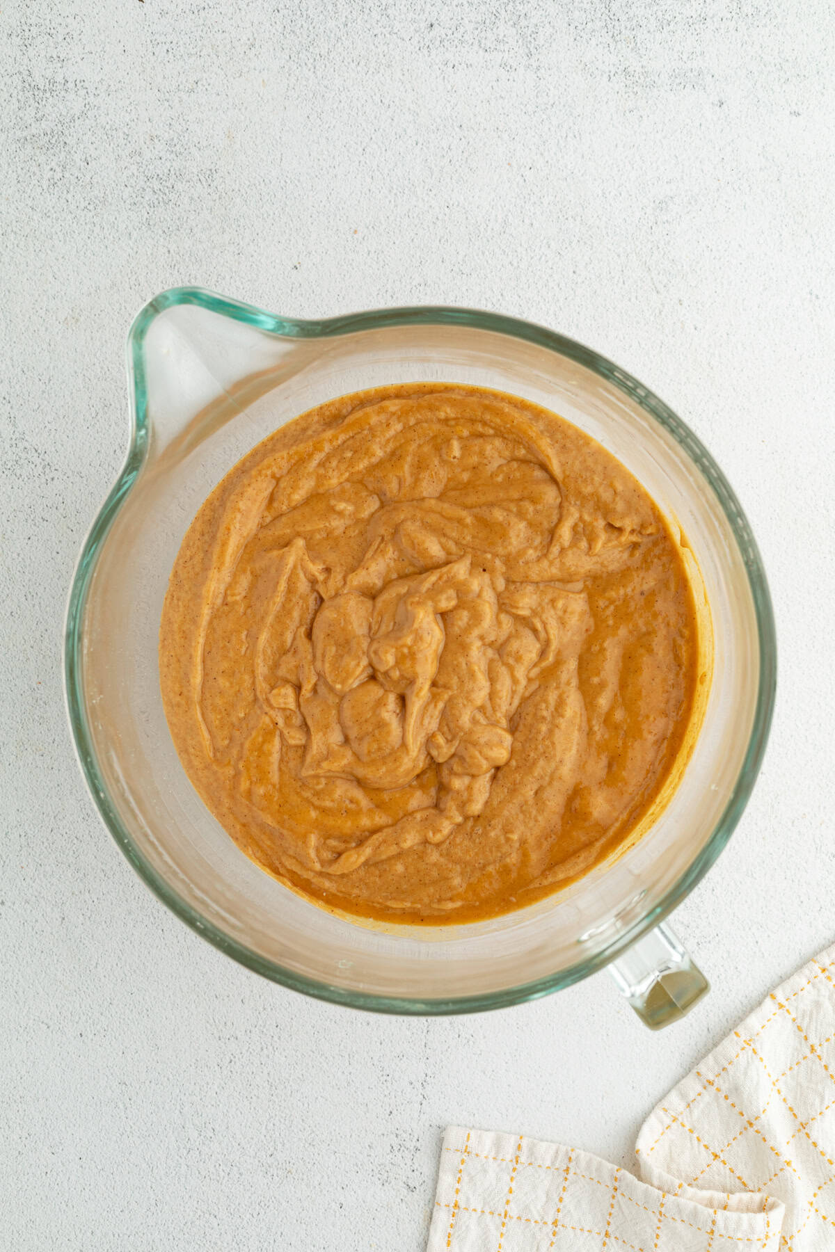 Pumpkin coffee cake batter in a large glass mixing bowl with a spout.