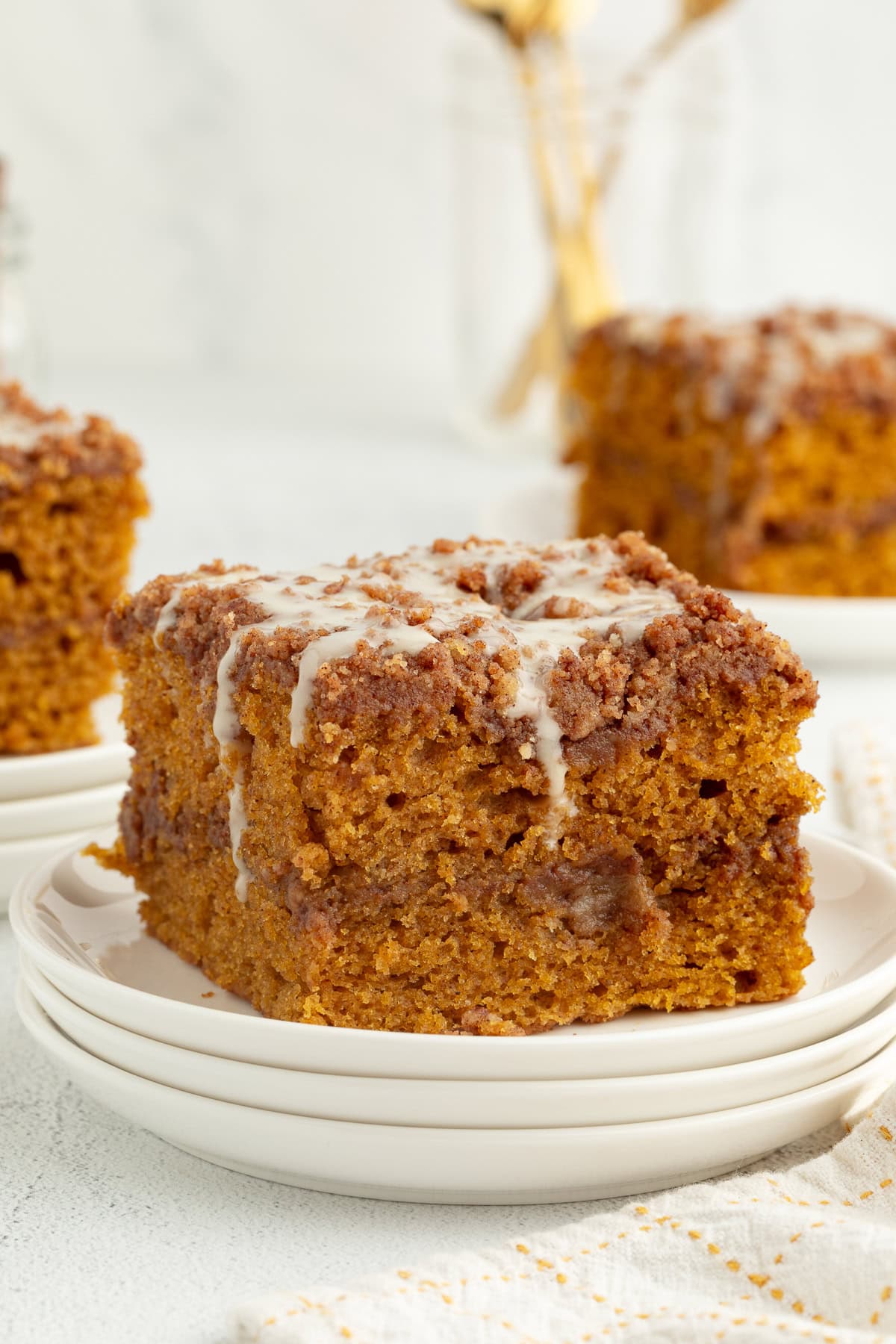 A slice of pumpkin coffee cake topped with glaze on a plate.