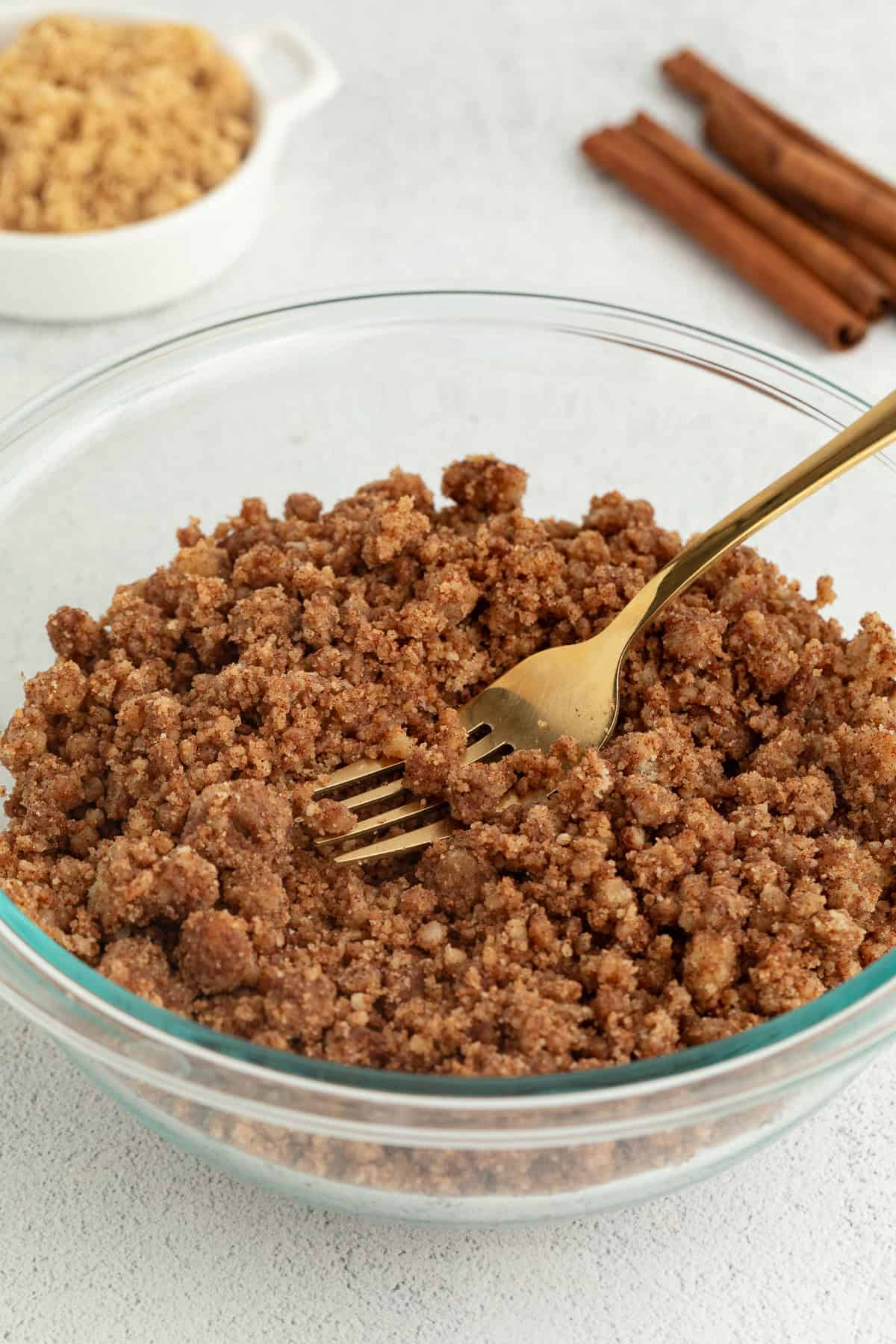 A fork resting in a glass bowl of streusel topping.