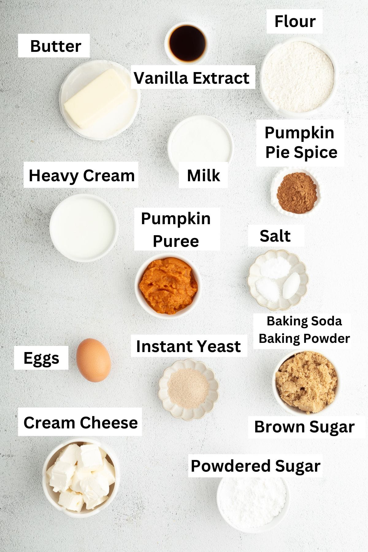 Pumpkin cinnamon rolls ingredients with text labels overlaying each ingredient.