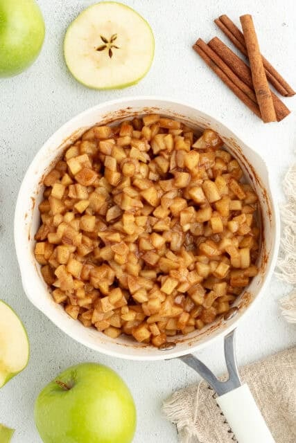 Overhead view of stovetop apple pie filling in a large skillet.