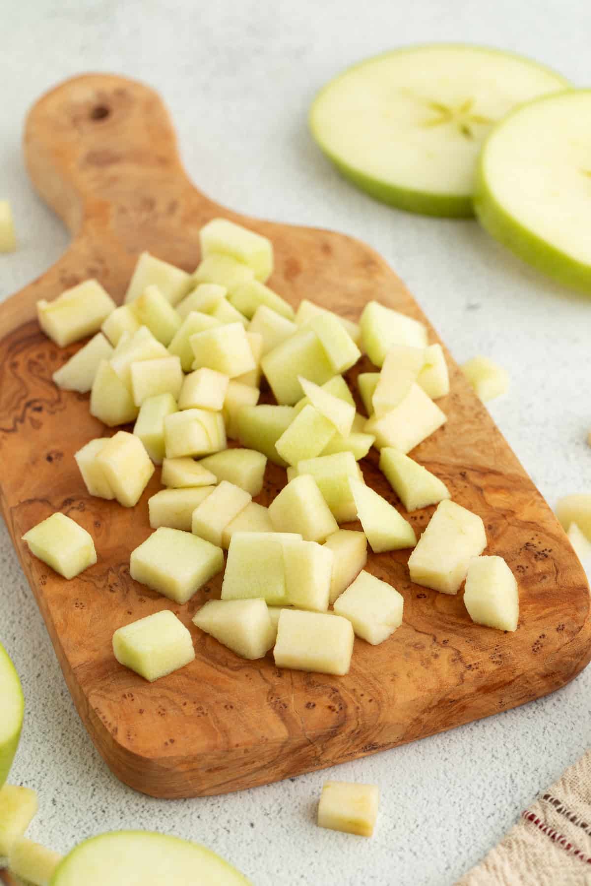 Diced Granny Smith apples on a wooden cutting board.