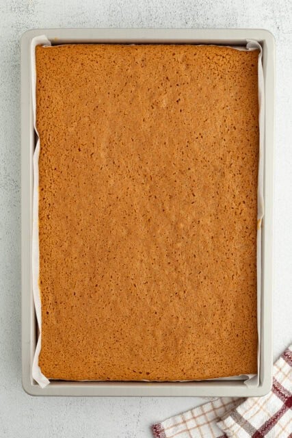 Baked pumpkin cake in a lined jelly roll pan.