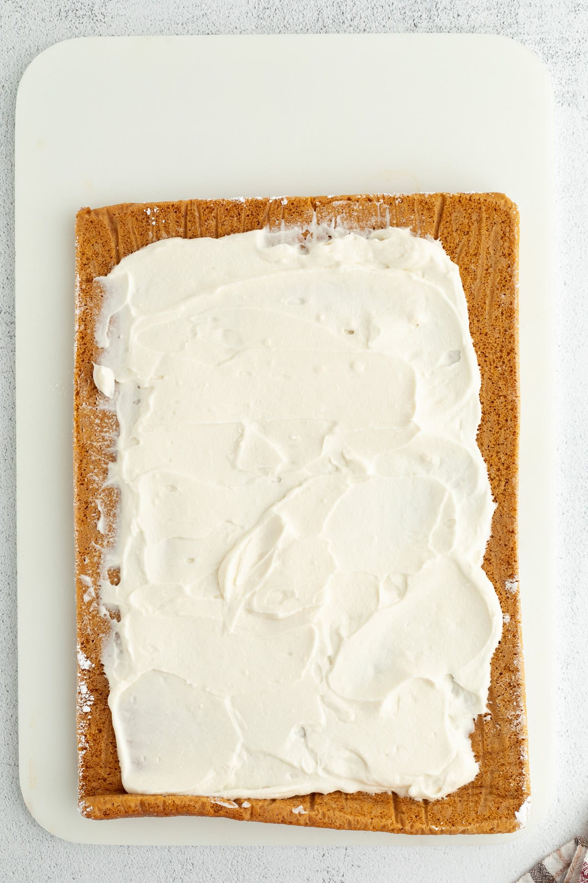 Mascarpone filling spread over a large jelly roll pumpkin cake.