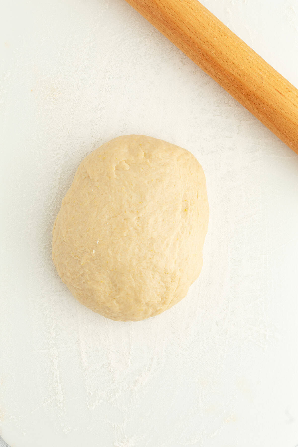 Homemade apple cinnamon rolls are golden-baked with warm cinnamon apple filling and topped with creamy brown butter cream cheese frosting. A ball of cinnamon roll dough next to a rolling pin.