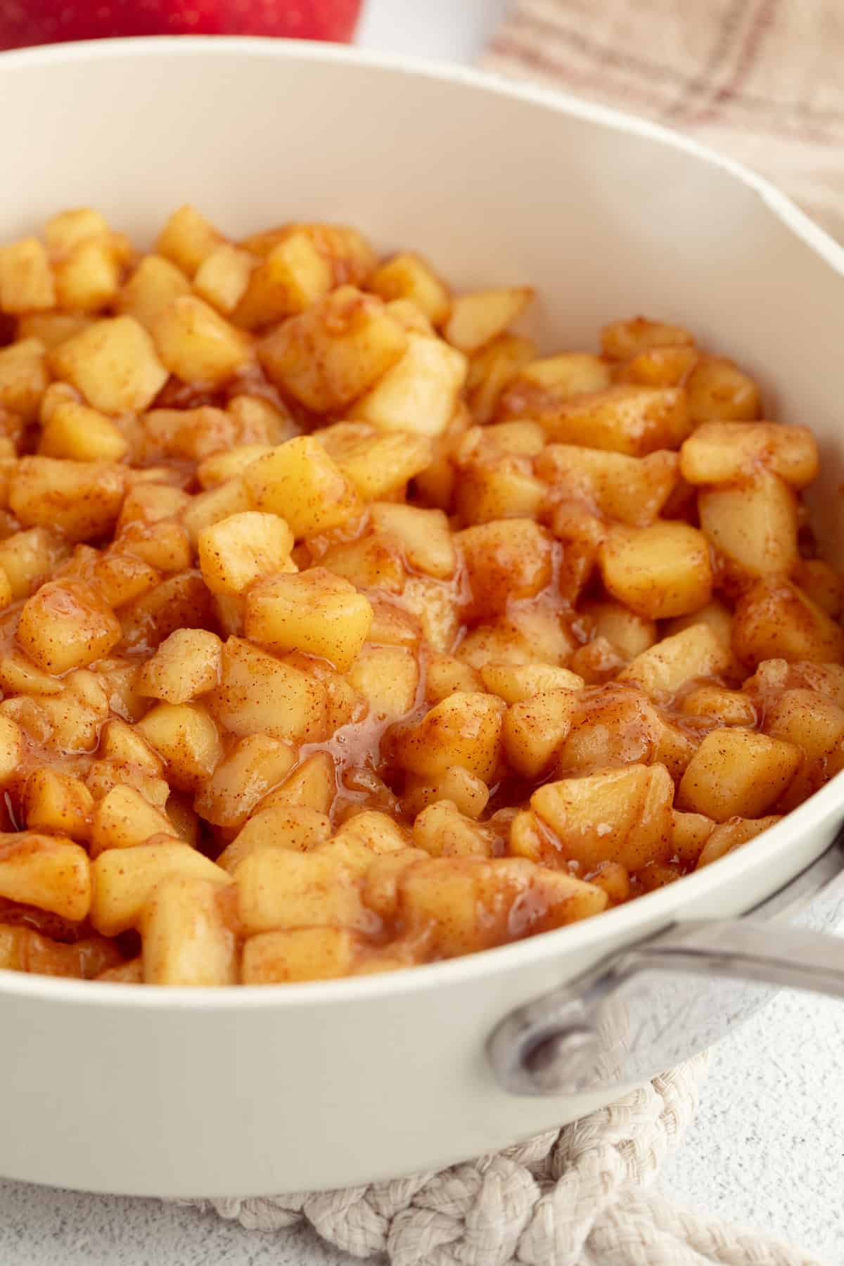 Homemade apple cinnamon rolls are golden-baked with warm cinnamon apple filling and topped with creamy brown butter cream cheese frosting. Homemade apple filling in a skillet.