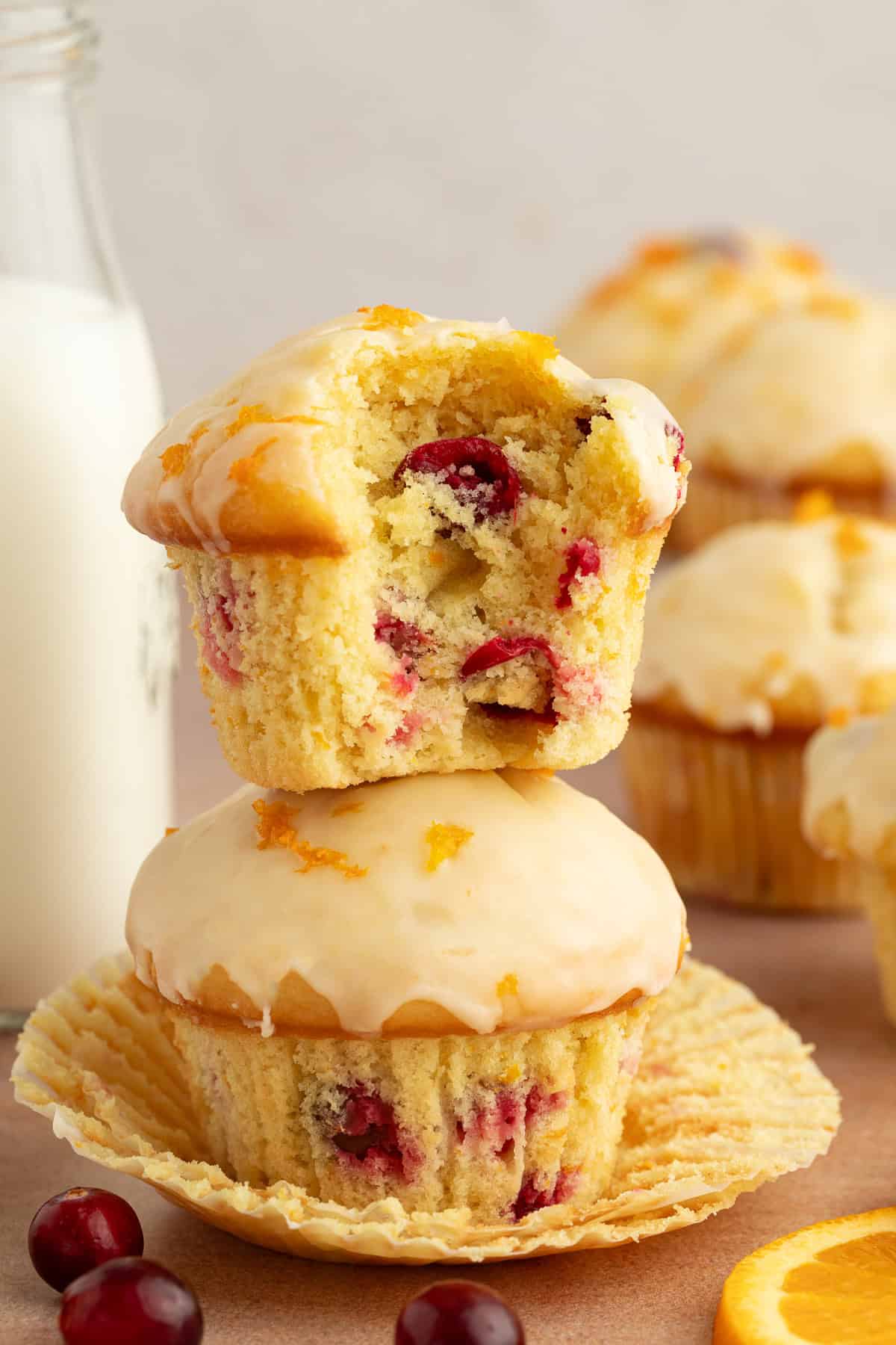 These moist cranberry orange muffins are full of real orange juice, fresh zest, and sweet-tart cranberries. So easy to make and big on flavor! A cranberry orange muffin with a bite missing, showing the fresh cranberries inside, stacked on top of a second muffin.