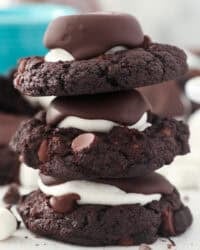 A stack of 3 hot chocolate cookies with a marshmallow in the middle and covered in chocolate