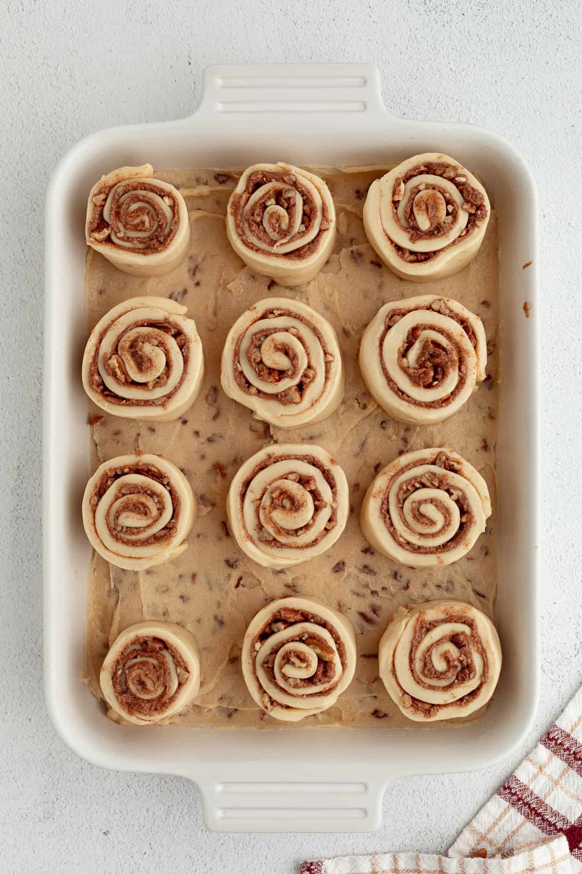 These homemade sticky buns are filled with warm cinnamon and nutty pecans, with a gooey caramel topping. The dough needs just 1 hour to rise! Overhead view of unbaked sticky buns in a baking dish before rising.