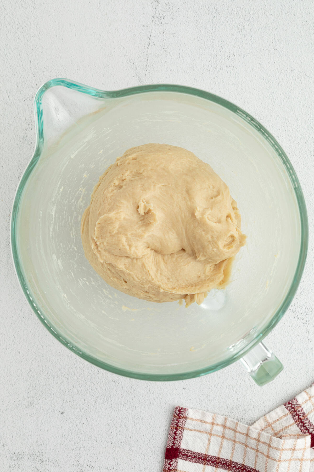 These homemade sticky buns are filled with warm cinnamon and nutty pecans, with a gooey caramel topping. The dough needs just 1 hour to rise! Cinnamon roll dough in a glass mixing bowl.