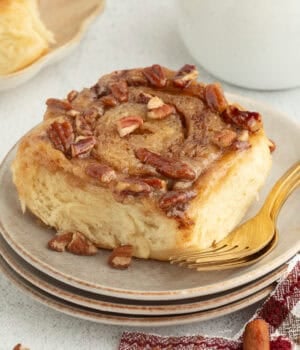 A sticky bun topped with caramel and pecans on a plate.