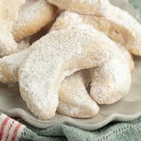 Close up of almond crescent cookies piled on a plate.