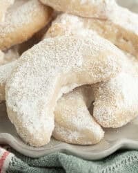 Close up of almond crescent cookies piled on a plate.